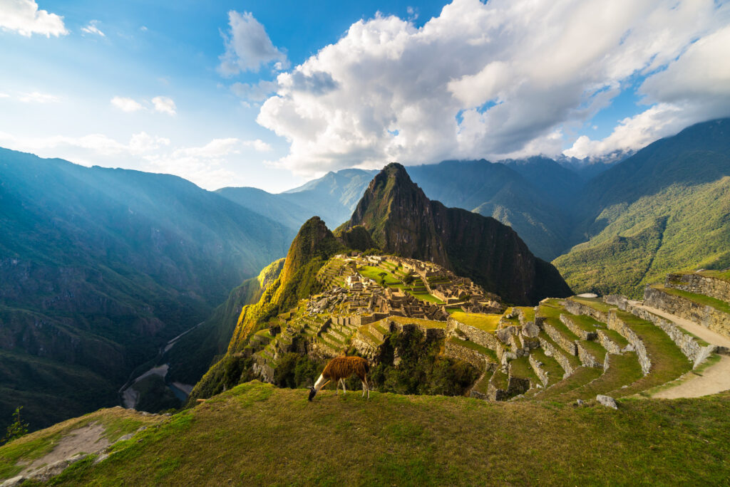 machu-picchu-illuminated-by-the-warm-sunset-light-wide-angle-view-from-the-terraces-above-with-scenic-sky-and-sun-burst (1)